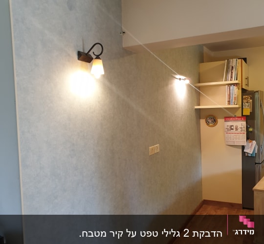קיר עם טפט כחול ומנורות קיר דולקות